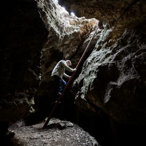 Travis Pickering descends a ladder into a cave